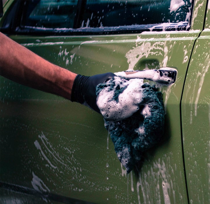 A green car door getting washed with soapy water