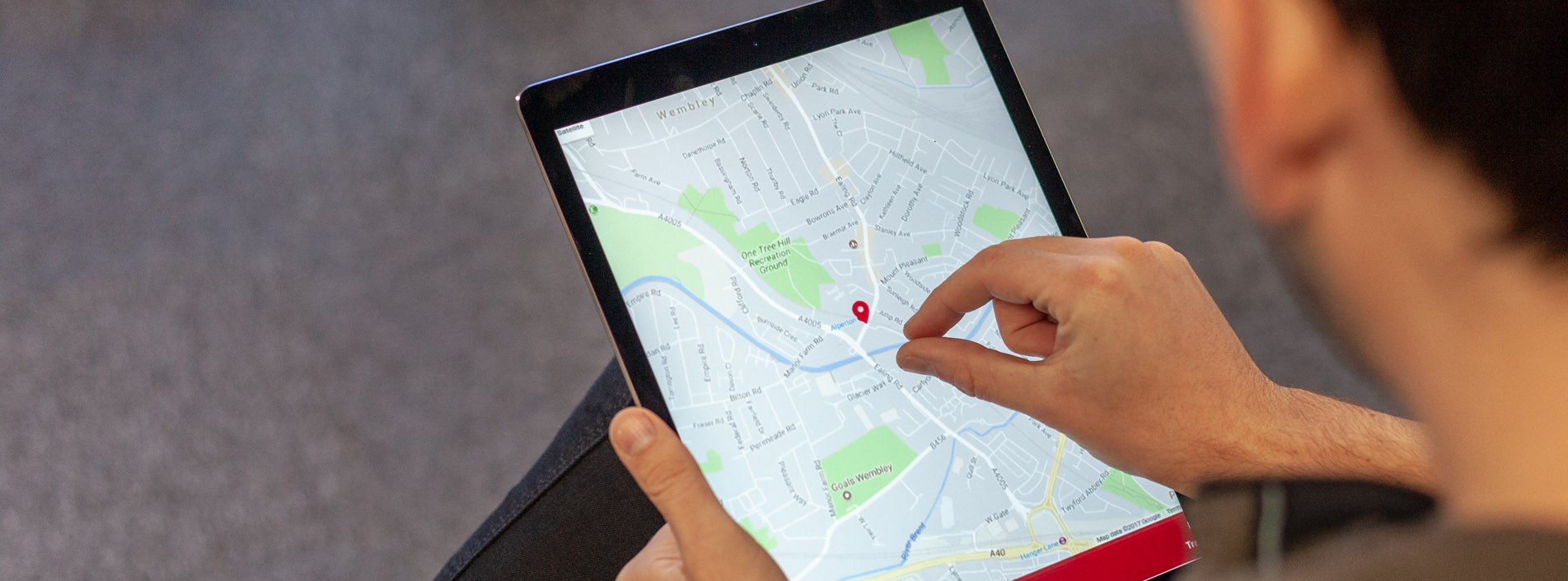 man zooming in on ipad, showing google maps location for custom development manchester