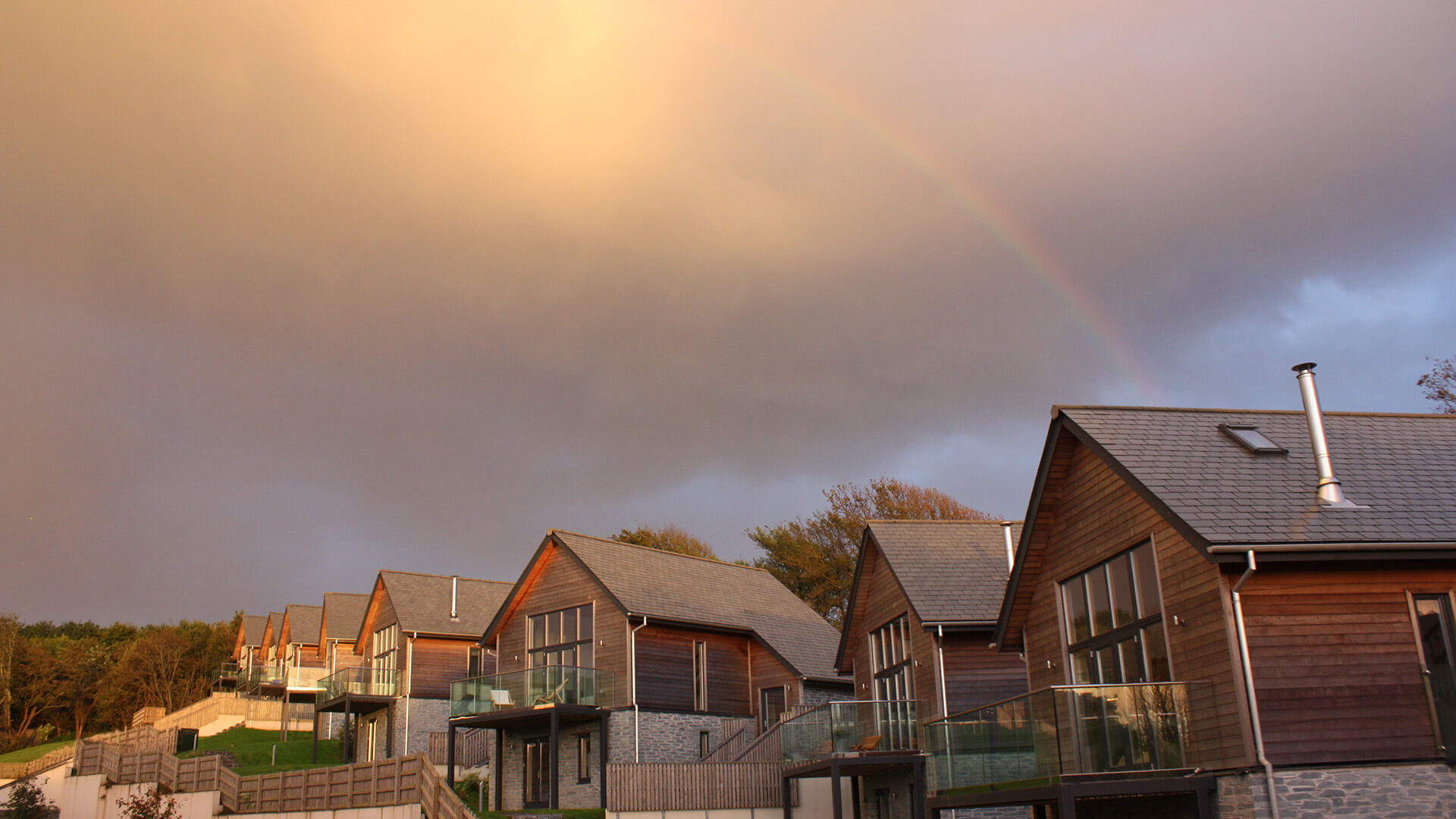 Grey skies with a rainbow tower over a range of houses with balconys
