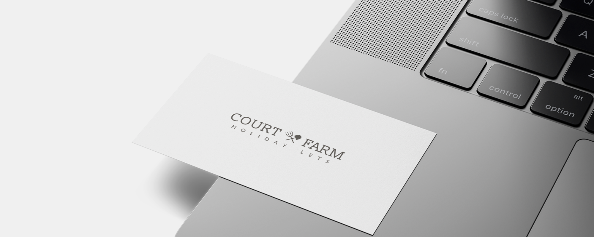 court farm business card with thier new agricultural branding logo on, sitting on the side of a laptop