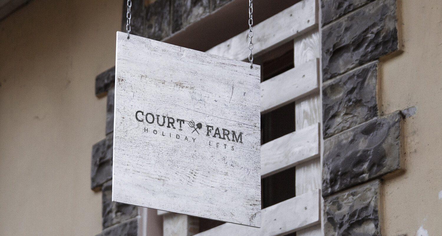 A swinging wooden sign displaying the agricultural branding logo done for court farm