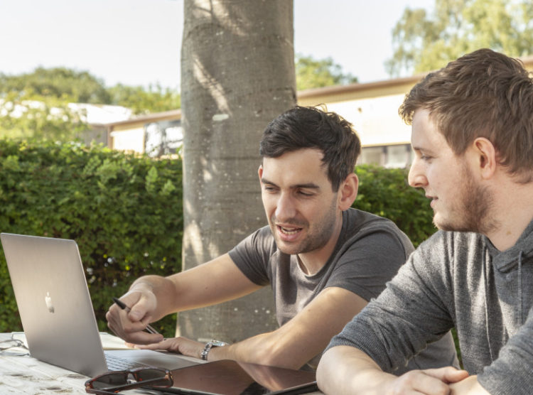 two gloversure team members working outside with laptop and notepads