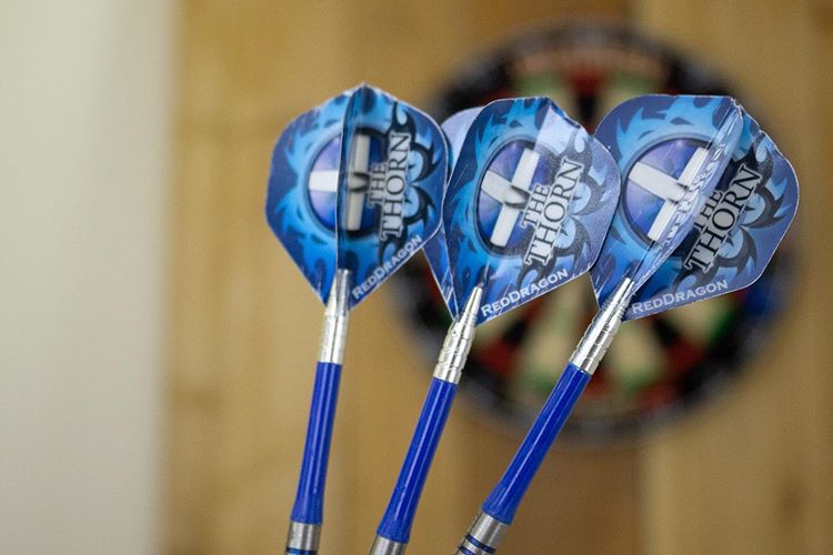 Three blue darts in front of a darts board