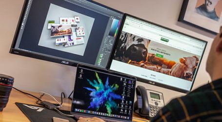 web designer creating marketing designs on multiple screens in an office