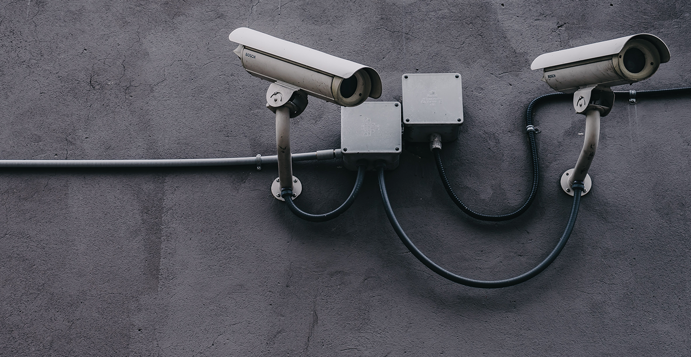 two security cameras mounted to a grey wall
