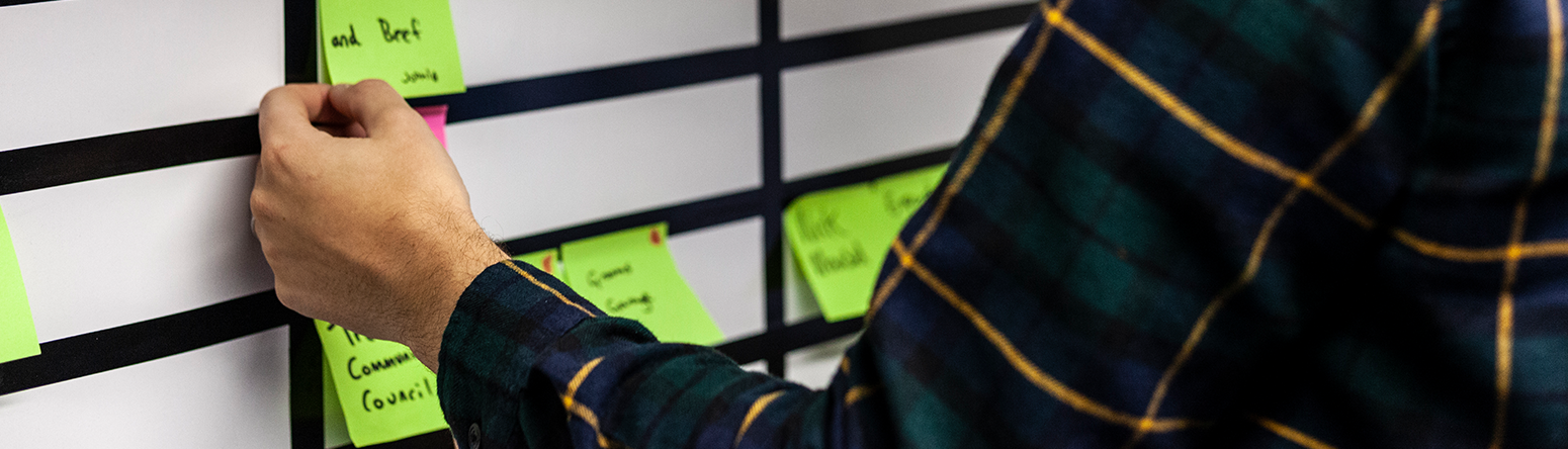A Project Manager putting post it notes with projects on a whiteboard