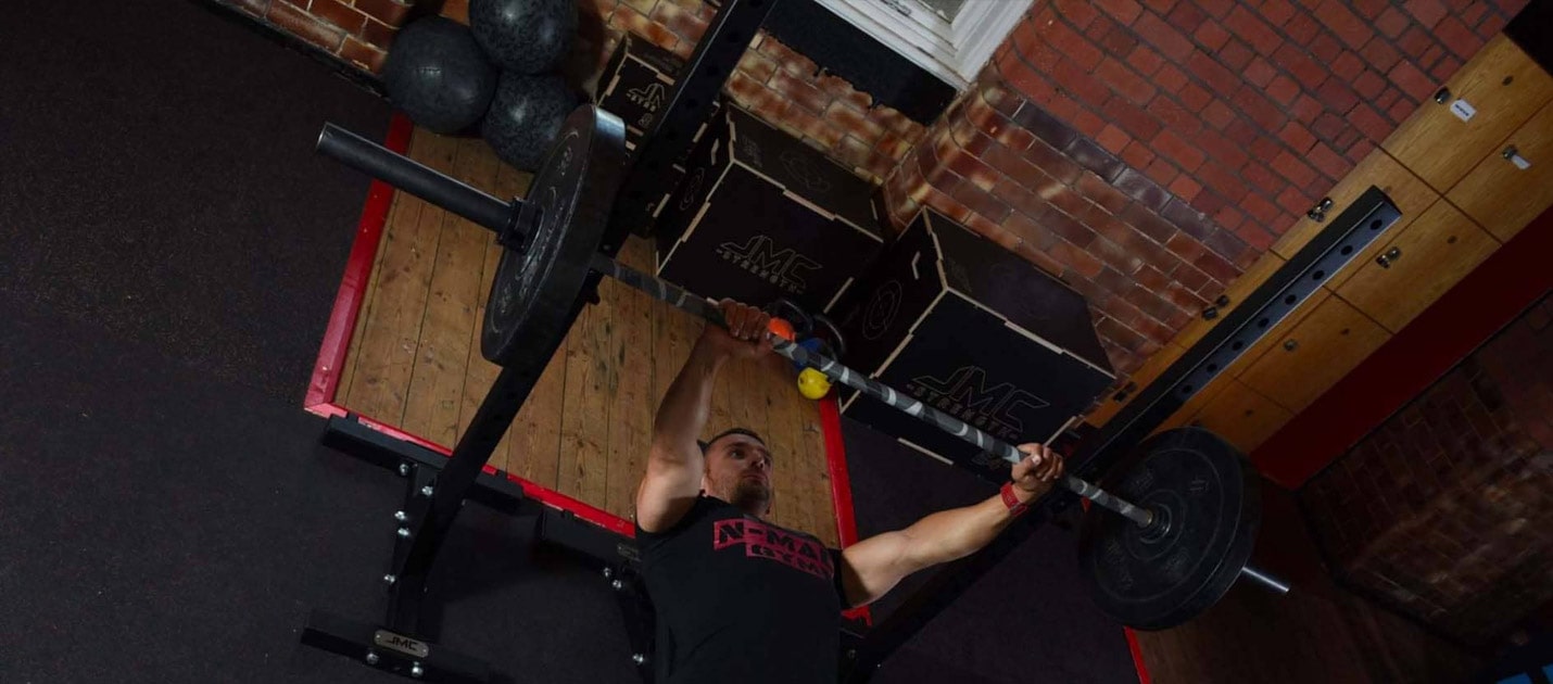 male gym member performing a bench press at JMC Strength gym