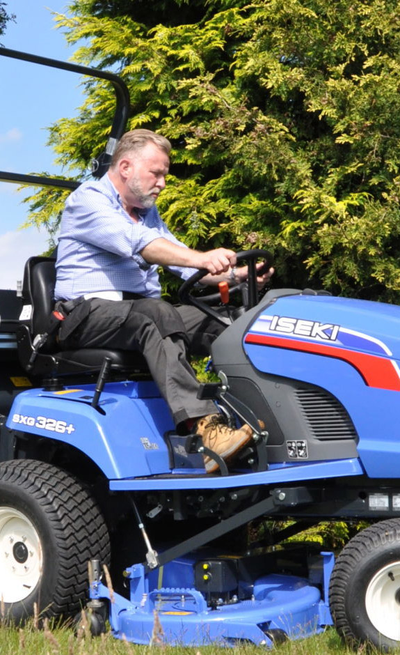 A business owner using the iseki SXG326 ride-on lawnmower