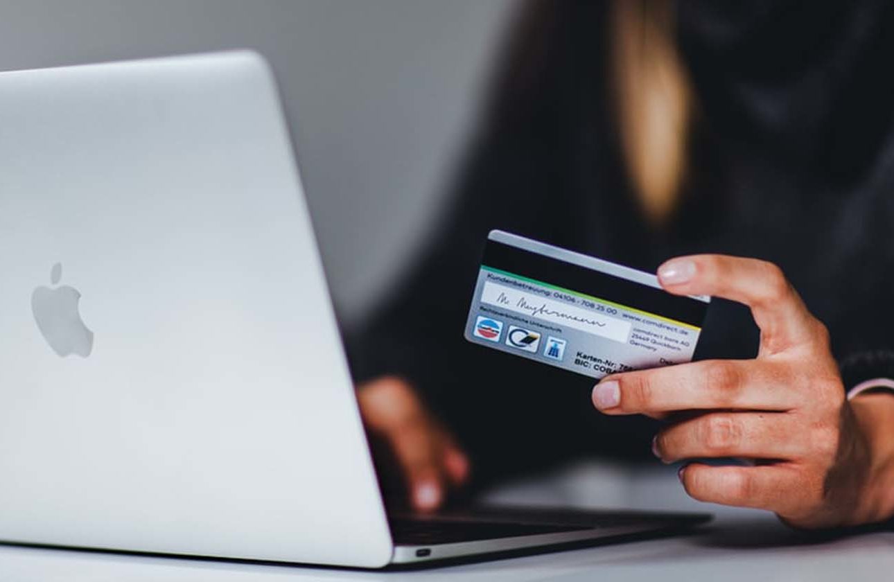 Someone purchasing something online through an ecommerce store on a laptop, holding a debit card