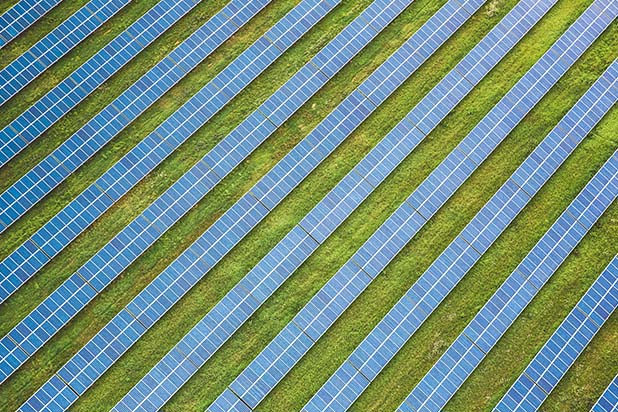 rows of a sustainable development of solar panels in a green field from a birds eye view