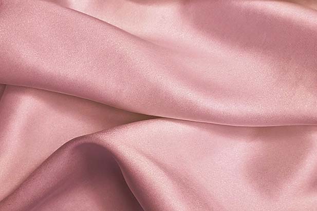 a close up image of a silky pink bed sheet