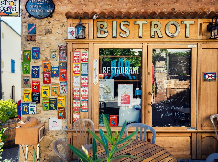 The outside of an old local rustic bistrio covered in small colourful posters with outside seating