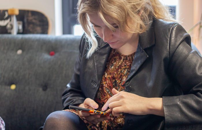 A female mobile ux agency team member sitting on a sofa looking down at their phone