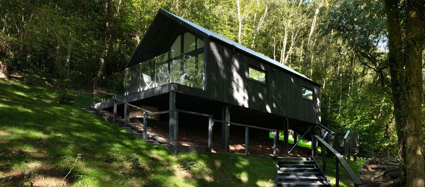A dark wooden cabin in a woodland setting